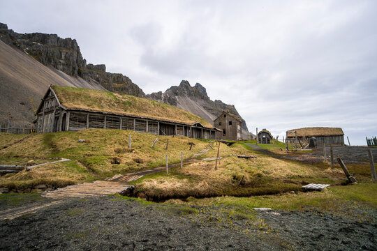 Traditional turf-roof farm beneath Icelandic mountain cliffs