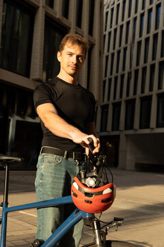Young man with bicycle and helmet in city sunlight