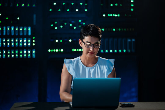 Woman working on laptop in server room