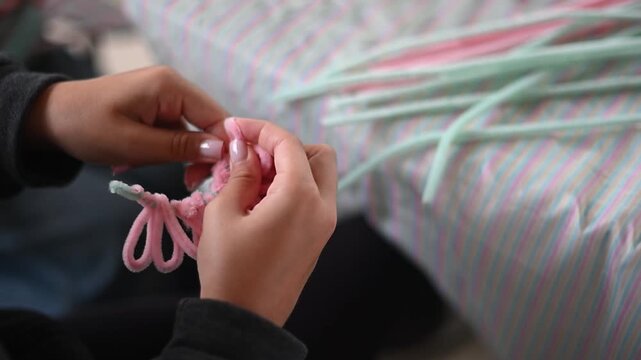 Child's hands twisting pipe cleaner for diy art project during a creative workshop close of handmade crafting up