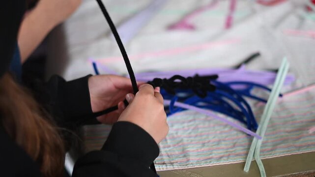 Child's hands twisting pipe cleaner for diy art project during a creative workshop close handmade crafting up