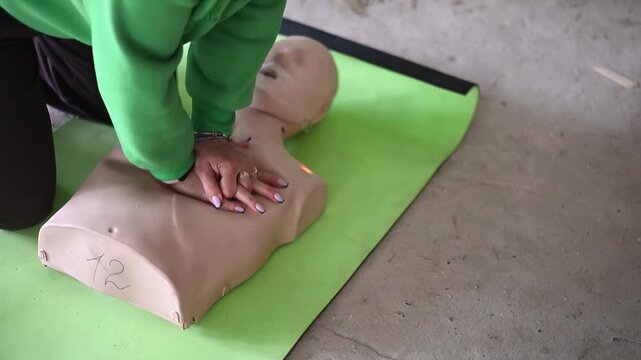 First aid instructor demonstrating cpr chest compressions on a medical training manikin during a lesson