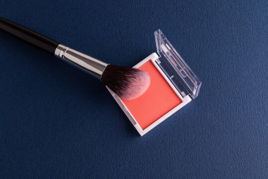 Blush palette with makeup brush on dark blue background