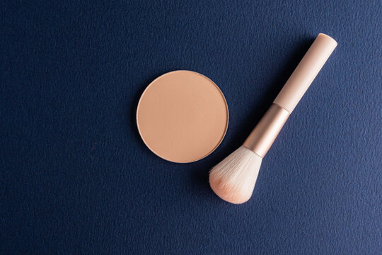 Autumn makeup powder and brush on dark blue background