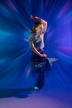 Young woman dance in colorful neon light studio
