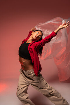 Latin woman dancer with flowing fabric in red studio
