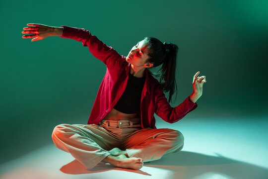 Latin woman dancer pose in dramatic colored studio light