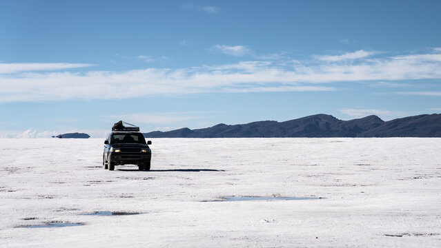Off-road vehicle crossing Salar de Uyuni salt flat