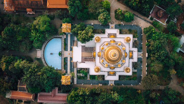 Aerial view of Buu Long Pagoda featuring its golden stupa, intricate architectural details, and a serene blue pool surrounded by lush green trees in Ho Chi Minh City, Ho Chi Minh, Vietnam.