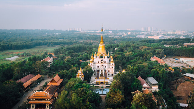 Aerial view of Buu Long Pagoda with its golden stupa surrounded by lush green trees and traditional architecture in Ho Chi Minh City, Ho Chi Minh, Vietnam.