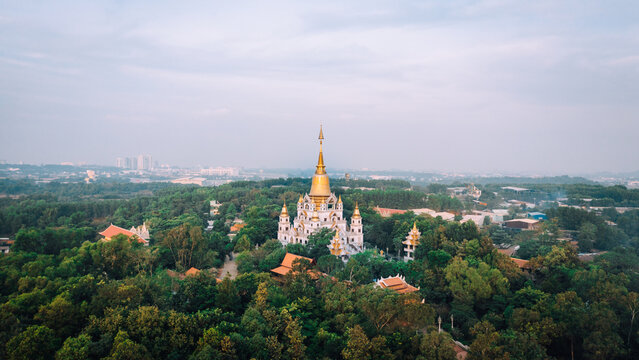 Aerial view of Buu Long Pagoda surrounded by lush green trees and forest under a soft sky in Ho Chi Minh City, Ho Chi Minh, Vietnam.