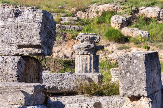 Fragmented Ionic column base among ancient stone ruins in Corinth, Greece