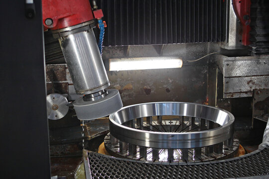 Close-up of the grinding or machining process of a metal bearing on an industrial machine with a coolant supply. Industrial photography. Metalworking machine