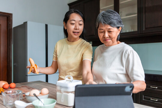 Asian mother and daughter cook together in kitchen