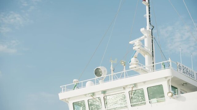 White ship bridge with radar mast and searchlight against blue sky