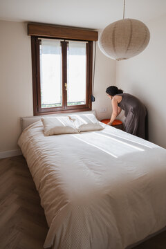 Woman arrange bedroom in modern apartment interior