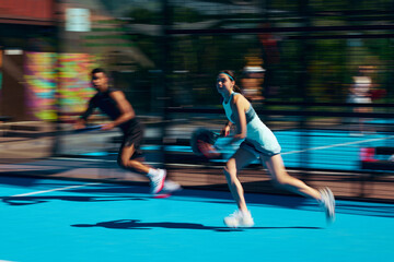 Obraz premium Stylish mixed padel pair running across court in coordinated sportswear with motion blur. Concept of couple activewear campaign, dynamic lifestyle fashion, sports partnership style.