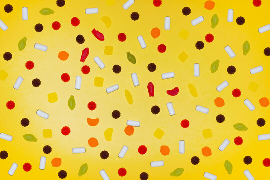 Colorful candy assortment on bright yellow background