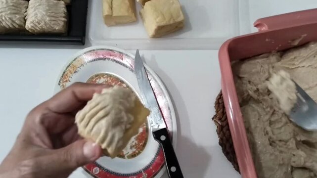 The ongoing process of filling fried tofu with meatball mixture (tofu bakso).