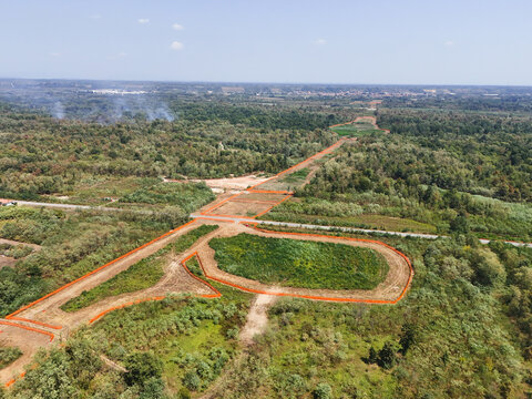 Aerial view of highway construction site cutting through the Baraggia natural landscape with orange safety fencing and cleared land in Gattinara, Piedmont, Italy.