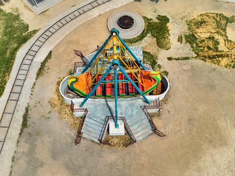 Aerial view of the colorful pirate ship amusement ride at Kashmir Park, surrounded by paved walkways and park grounds in Dera Ghazi Khan, Punjab, Pakistan.