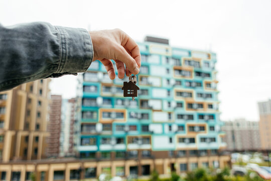 Man holding house key in front of apartment building