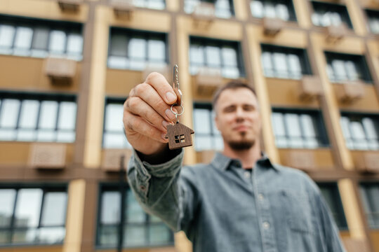 Homeowner hold house key in front of apartment building
