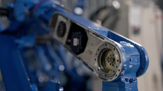 Close-up blue robotic arm assembly shows exposed mechanical joint and motor at industrial facility, prepared for customer-specific factory automation, engineering, maintenance, productivity.