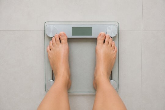 Bare Feet Standing on Digital Bathroom Scale with Blank Display
