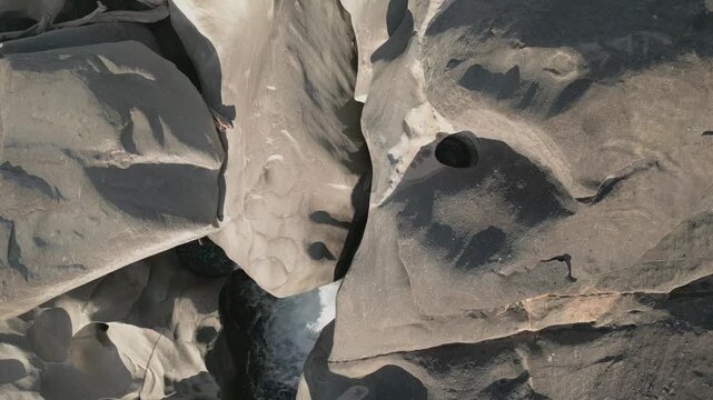 Quartzite solution pothole and fluvial slot channel along the Sao Miguel River at Vale da Lua, Chapada dos Veadeiros National Park, Brazil, top down drone forward flyover.