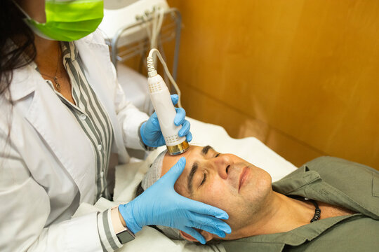 Doctor performing facial treatment at beauty clinic