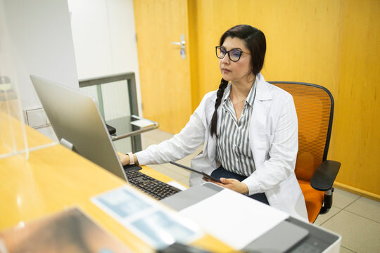 Female doctor using laptop at medical clinic reception