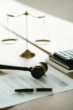 Judge's gavel beside a contract document and scales of justice on a desk, symbolizing legal agreements, law, justice, courtroom decisions, and legal services.