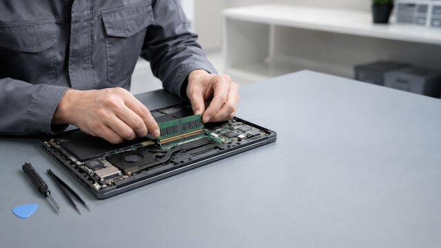 Technician installing memory module inside open laptop
