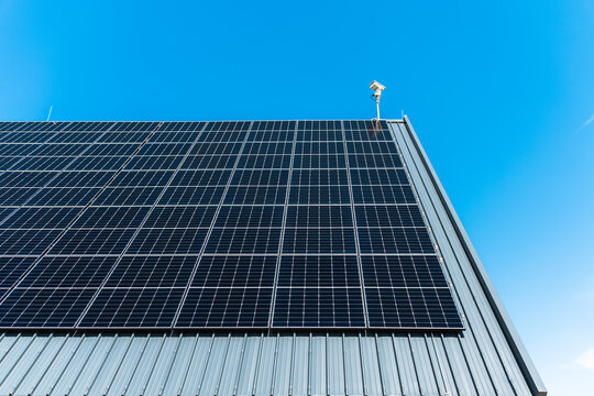 Solar panels on industrial roof under clear blue sky