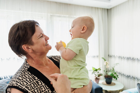Grandmother hold laughing baby at home