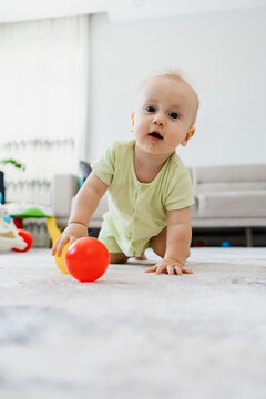 Baby crawl with red ball on living room floor