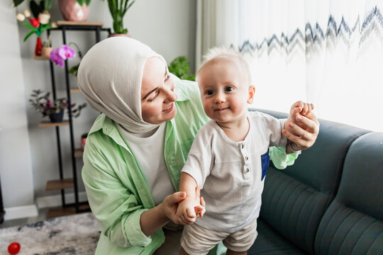 Muslim mother hold smiling baby at home