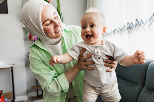 Muslim mother hold smiling baby at home