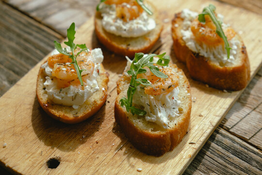 Bruschetta or crostini with cream cheese, shrimp and arugula. Tasty snacks.