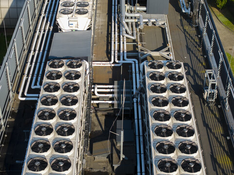 Aerial view of an AI data center cooling system with rows of industrial fans and complex piping on a rooftop in Krakow, Lesser Poland Voivode, Poland.