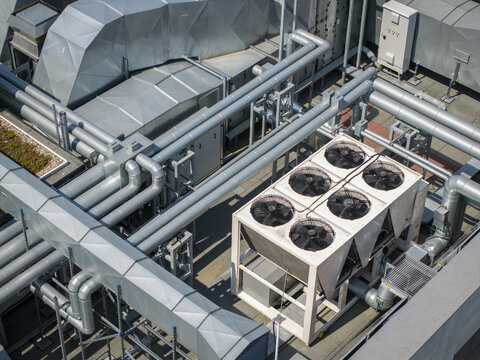 Aerial view of an industrial AI data center cooling system with large fans, metallic pipes, and ventilation ducts on a rooftop in Krakow, Lesser Poland Voivode, Poland.