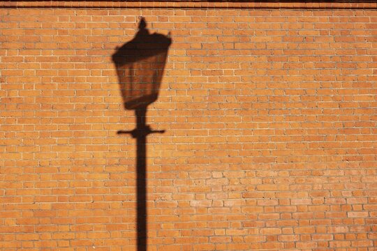 Shadows of a historic street lamp on reddish brown bricks in the evening light, Sloane Square, Borough of Chelsea and Kensington, London, England, Great Britain