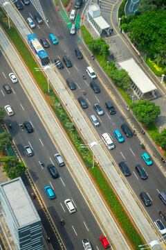 High-angle perspective of traffic flowing on Jalan Sudirman, a vital central business district artery in Jakarta, Indonesia. Mixed vehicles move along multi-lane roads under daylight.