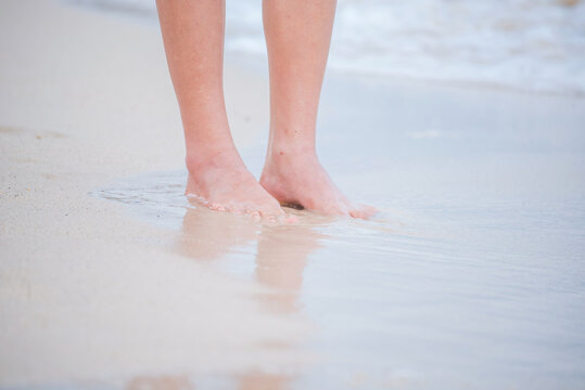 Woman walking barefoot summer beach. Close up legs walk along wave of sea water sand beach. Enjoy freedom barefoot leg walk outdoor. Relaxation Travel woman foot walking tropical summer beach