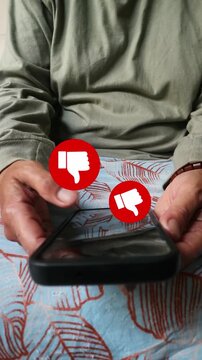 Person holding a smartphone showing red thumbs down icons representing negative feedback or social media disapproval.