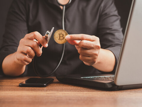 Person examining a cryptocurrency coin with magnifying glass