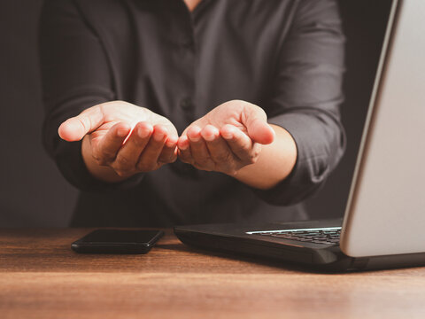 Person holding out open hands beside laptop