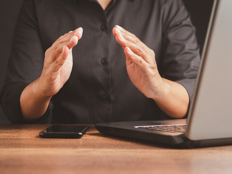 Person gesturing with open hands beside laptop