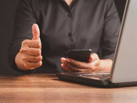 Person showing thumbs up while using smartphone